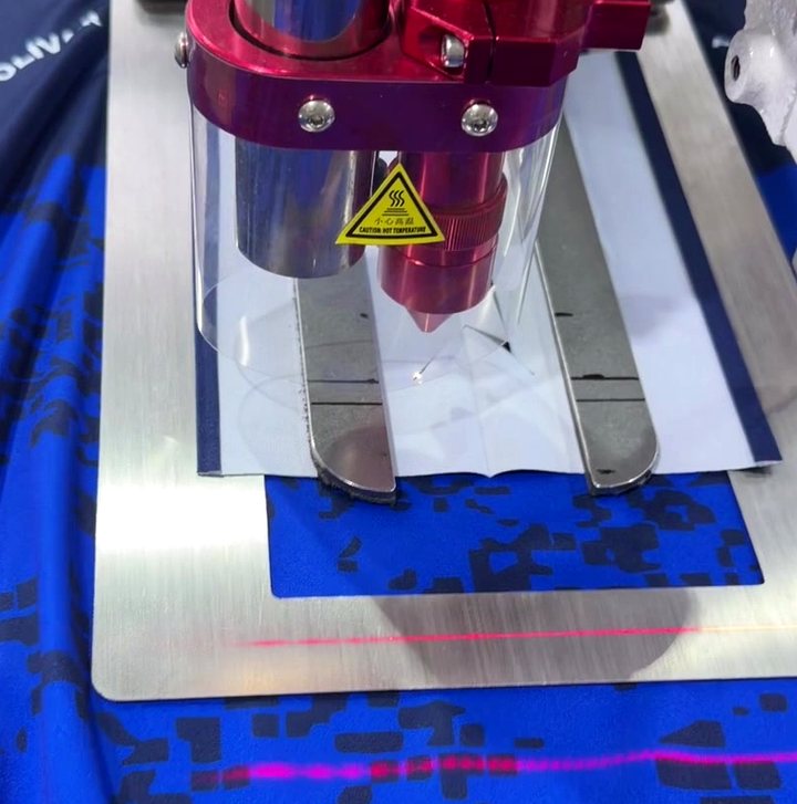 Ojaladora automática con guías láser trabajando sobre tela sublimada